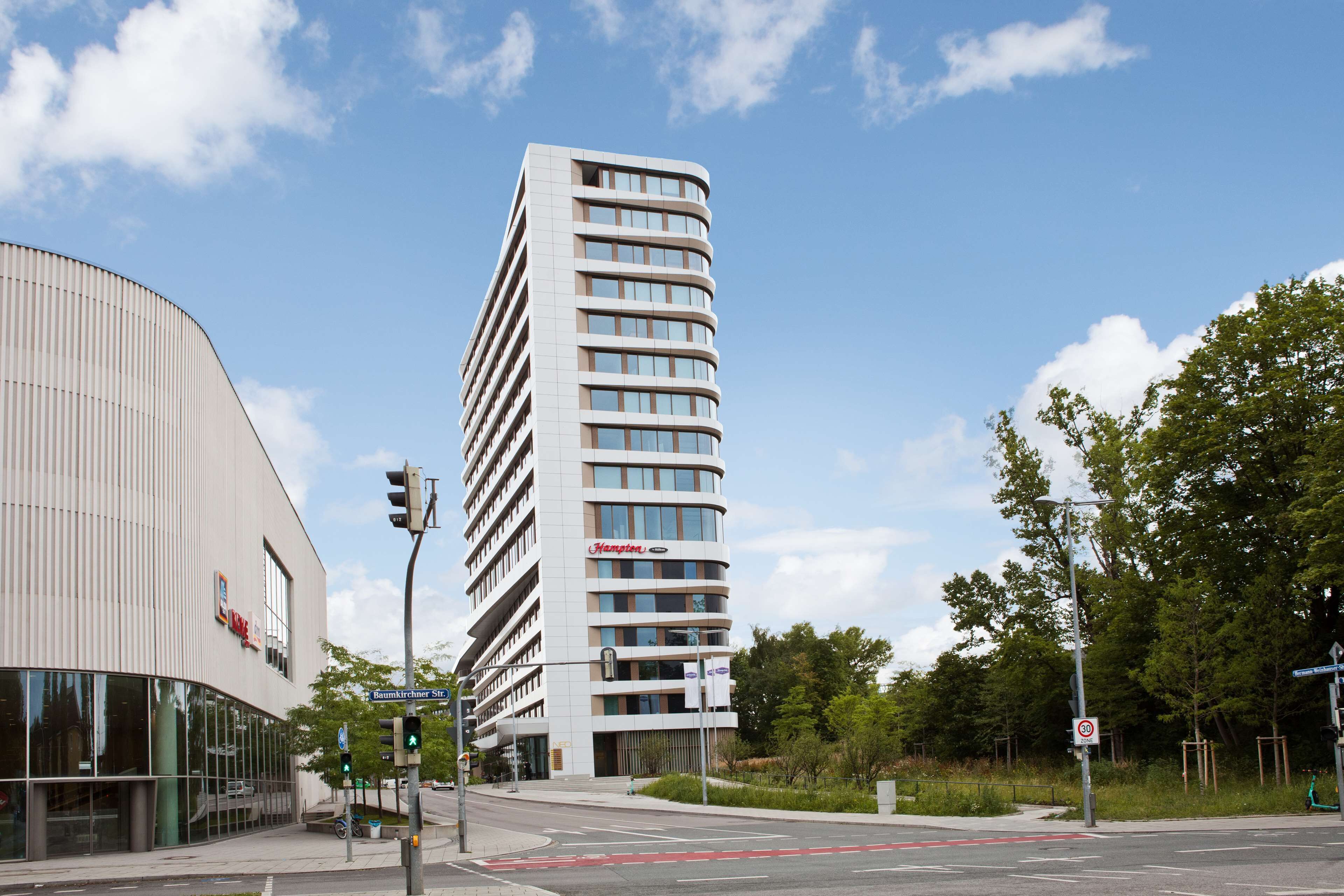 Un hôtel moderne à la façade incurvée, doté de grandes fenêtres et d’une enseigne « H&M » bien visible.