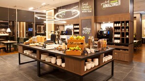 Un café moderno con un mostrador central que exhibe frutas y equipo para preparar café.