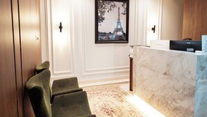 A hotel lobby with a reception desk, a framed picture of the Eiffel Tower, and a patterned carpet. - Paris Hotel by H Hotéis Business (Taguatinga)