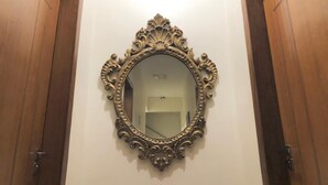 A mirror with an ornate gold frame on a white wall, flanked by wooden doors. - Paris Hotel by H Hotéis Business (Taguatinga)
