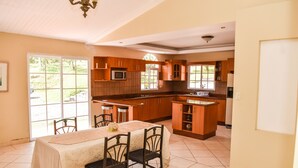 A spacious kitchen with a dining area, large windows, and a tiled floor.
