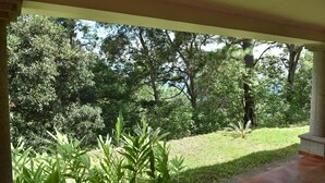 A covered outdoor area with a view of a lush garden and trees.