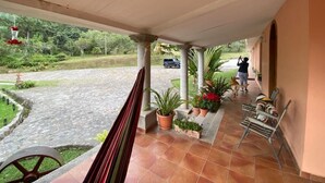 A covered outdoor area with a tiled floor, potted plants, and a hammock.