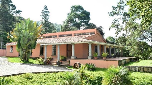 A two-story building with a red-tiled roof and a covered porch.