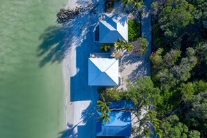 A beachfront property with multiple buildings, a sandy beach, and surrounding greenery. - Windows on the Water "W.O.W"  An ocean front oasis!   (Captiva)