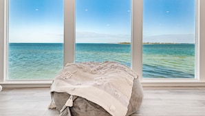 A room with a large window overlooking a body of water, a bean bag chair, and a light-colored floor. - Windows on the Water "W.O.W"  An ocean front oasis!   (Captiva)