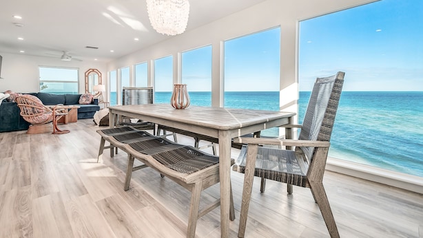 A spacious room with a large dining table, wicker chairs, and a view of the ocean. - Windows on the Water "W.O.W"  An ocean front oasis!   (Captiva)