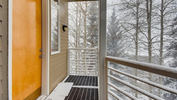Una porta di legno, una finestra e un balcone con ringhiera metallica.