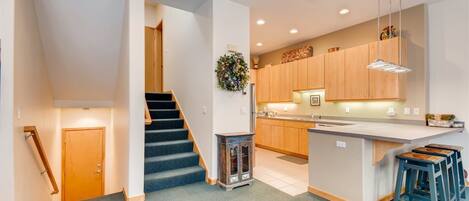 A modern kitchen with wooden cabinets, a central island, and bar stools.