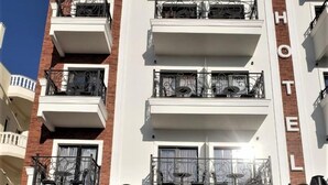 Un hotel con varios balcones, mobiliario exterior y una vista despejada del cielo.