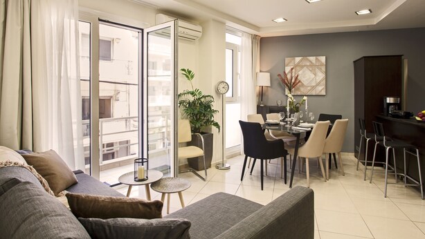 Una sala de estar moderna con sofá, mesa de comedor, sillas y un balcón con puerta corrediza.