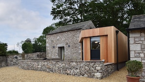 A stone building with a wooden extension, a gravel driveway, and a potted plant.
