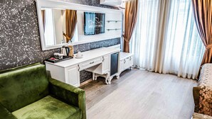 A modern hotel room with a green sofa, a white vanity with a mirror, and a bed with patterned bedding. - Lazz City Hotel (Istanbul)