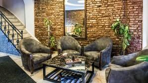 A modern living room with a stone wall, leather armchairs, a marble coffee table, and a staircase. - Lazz City Hotel (Istanbul)