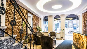 A modern interior with a brick wall, a staircase with ornate black railings, and a reception desk. - Lazz City Hotel (Istanbul)