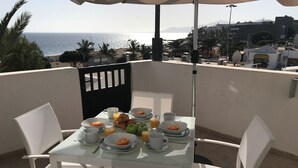 A table set for breakfast with a view of the sea and buildings in the background. - 5 Star,  2 x True  Ensuite’s, Beach 20 meters,  Pool,  AC, FREE WIFI, Full TV.  (Puerto del Carmen)