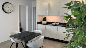 A modern kitchen with white cabinets, a black countertop, and a clock on the wall. - 5 Star,  2 x True  Ensuite’s, Beach 20 meters,  Pool,  AC, FREE WIFI, Full TV.  (Puerto del Carmen)