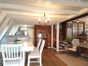 A cozy loft-style living space with a dining area, kitchen, and staircase leading to a loft bedroom.
