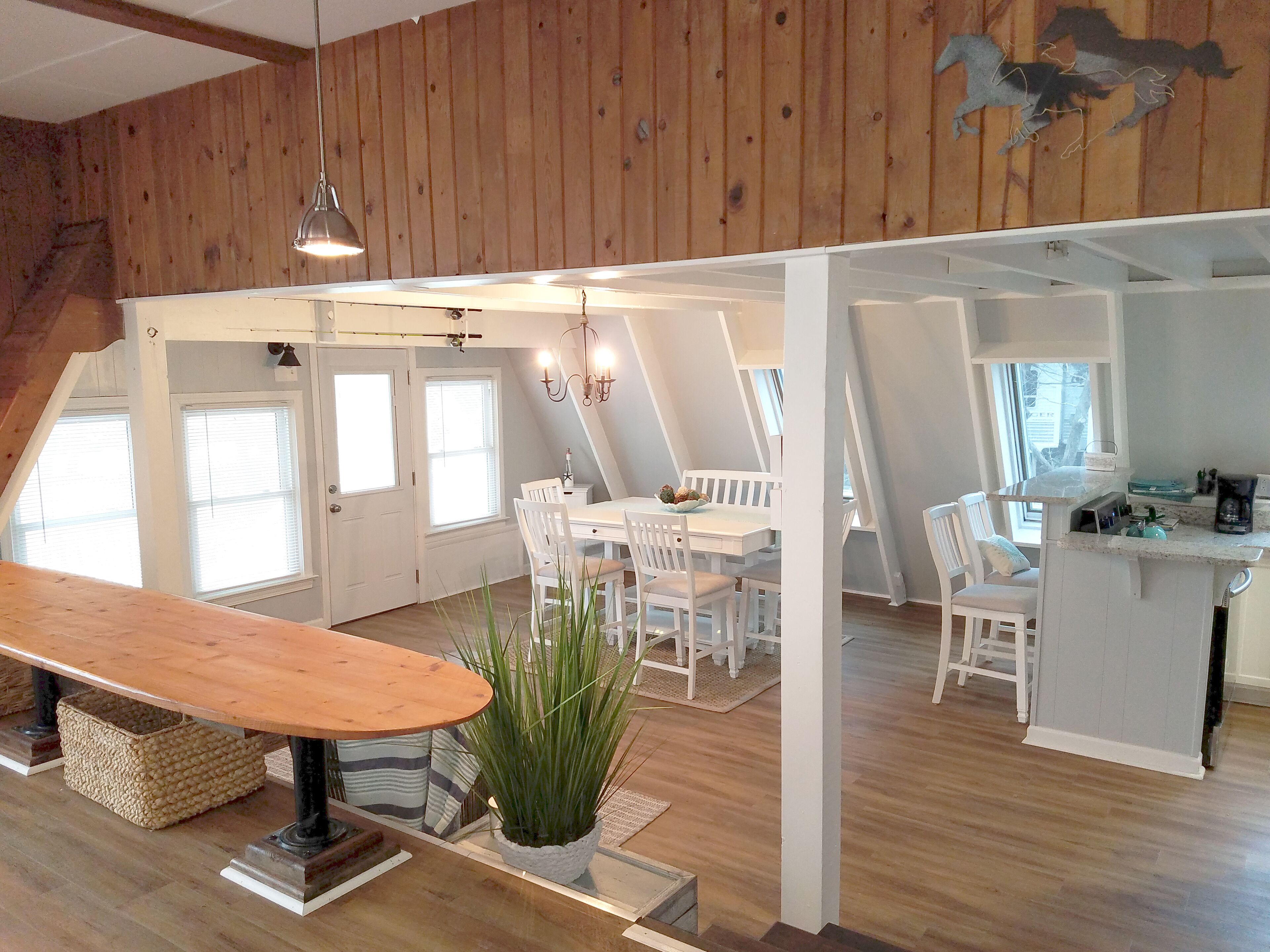 A loft-style room with a dining area, kitchen, and a large window.