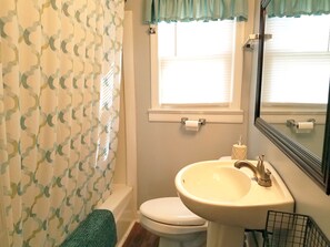 A bathroom with a toilet, sink, and shower curtain.