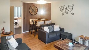 Ein modernes Wohnzimmer mit einem grauen Sofa, einem Holztisch und einem Essbereich mit einem Holztisch und Stühlen.