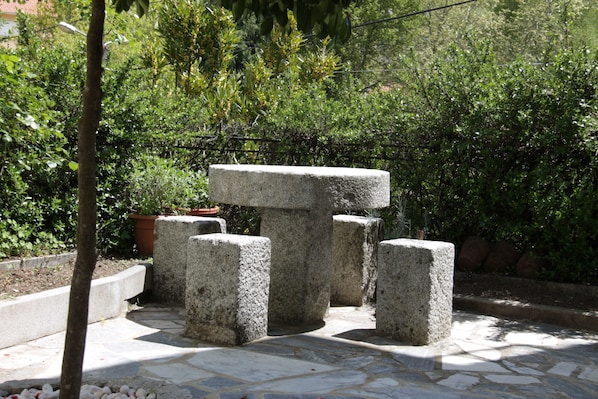 A stone bench with a simple, sturdy design in a garden area.