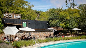 A pool area with a bar, outdoor seating, and a clear blue pool.