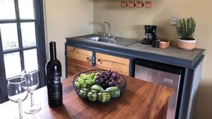 A kitchen with a wooden countertop, a sink, a coffee machine, and a potted plant.