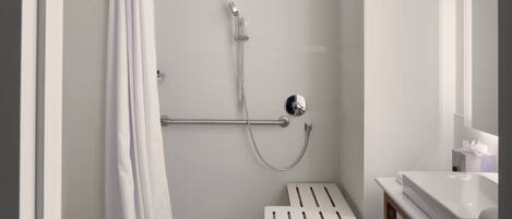 A modern bathroom with a shower, a grab bar, a sink, and a mirror.