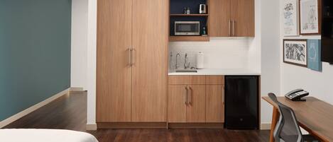 A compact kitchen with wooden cabinets, a microwave, and a dishwasher.