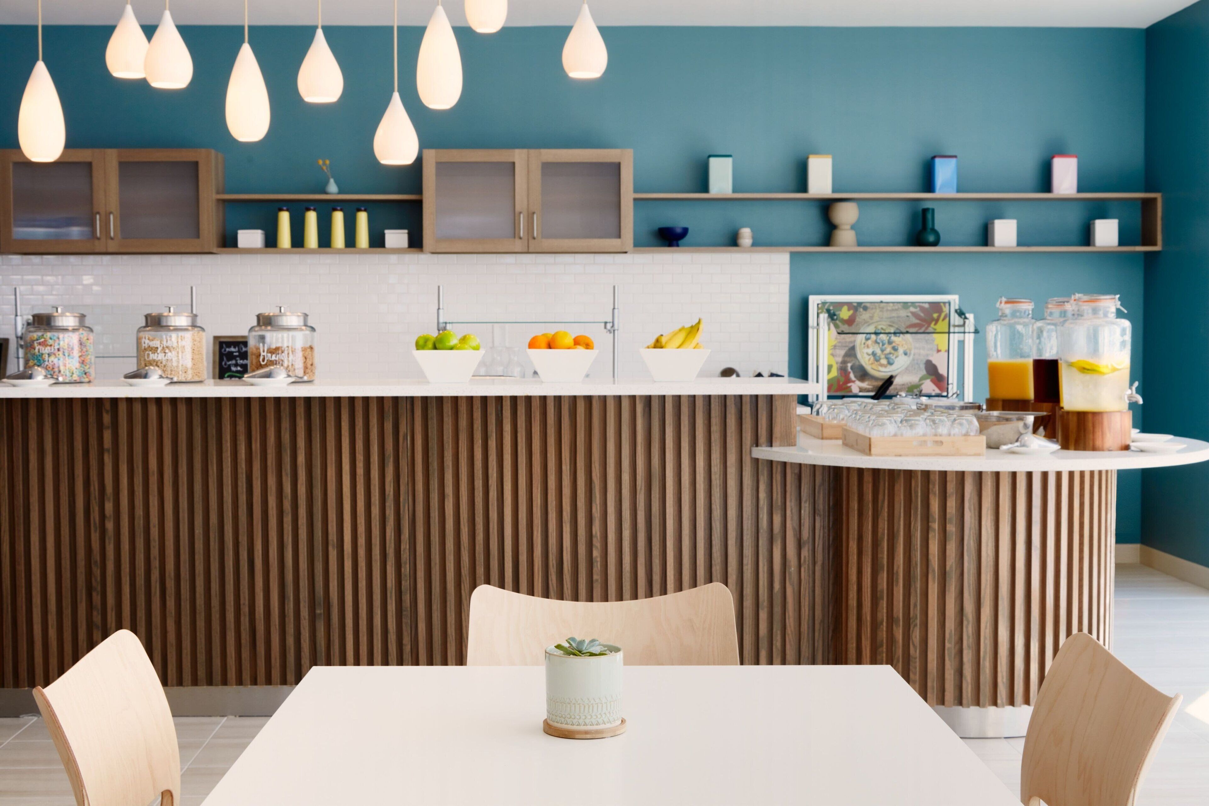 A modern kitchen with wooden cabinets, a white countertop, and hanging pendant lights.