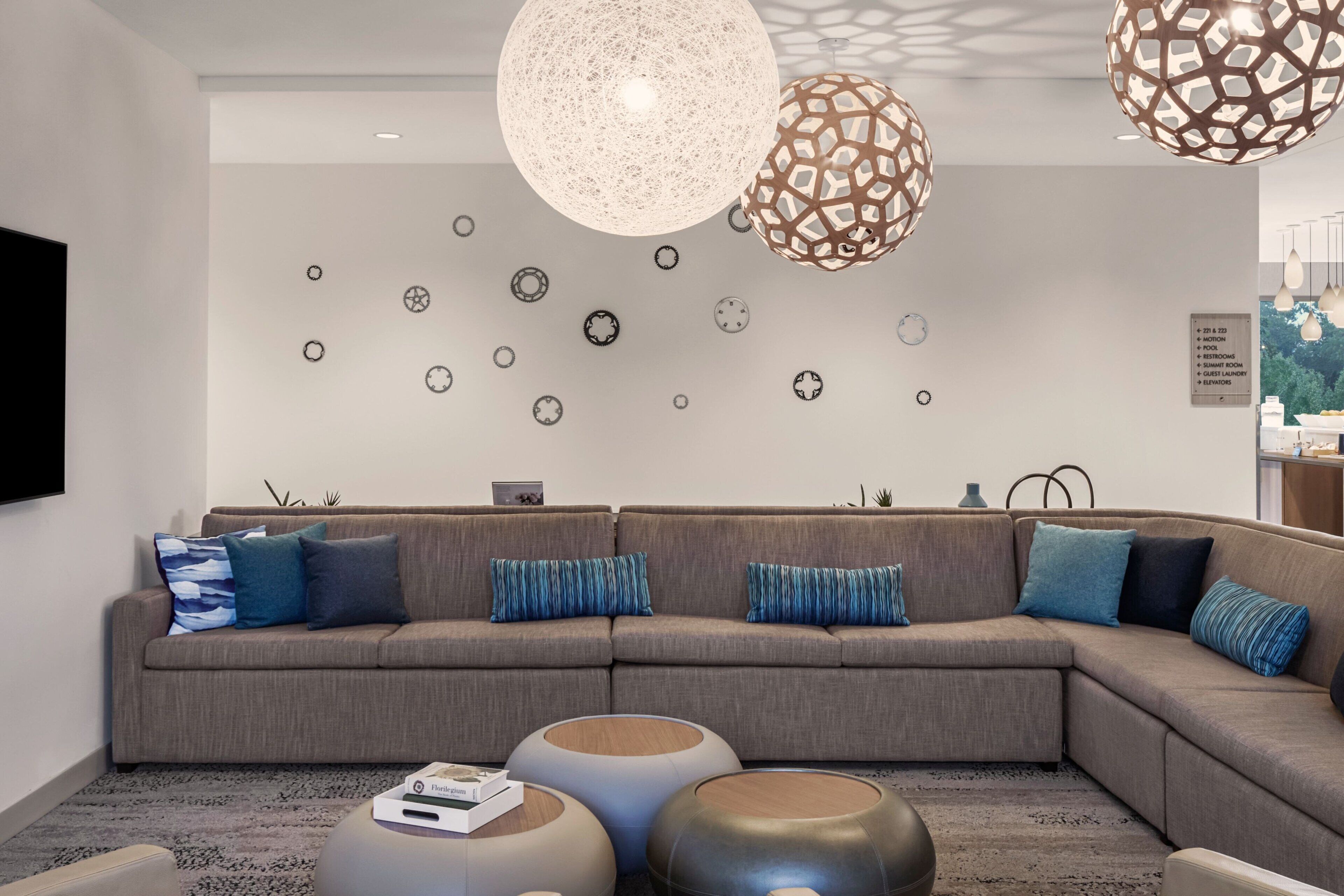 A modern living room with a sectional sofa, decorative wall art, and unique pendant lights.