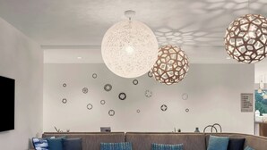 Ein modernes Wohnzimmer mit einem Ecksofa, zwei Sesseln, einem Couchtisch und dekorativen Wanduhren.