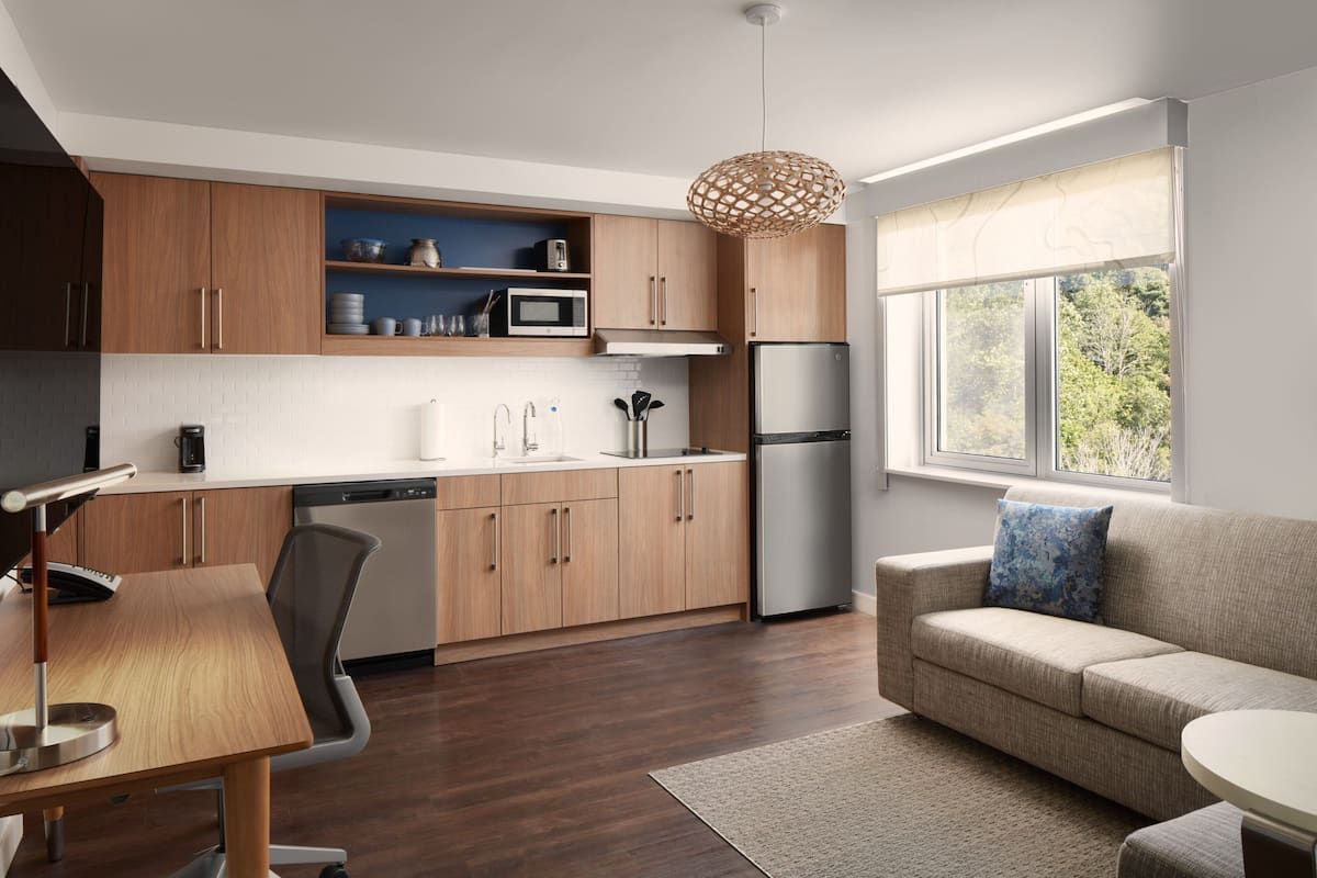 Een moderne keuken met houten kastjes, een ingebouwde magnetron en een roestvrijstalen koelkast.