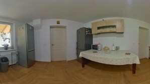 A compact kitchen with a dining table, built-in cabinets, and a small refrigerator. - Pensiunea Rozelor (Simbata de Sus)