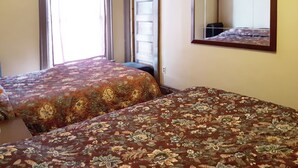 Ein Hotelzimmer mit zwei Betten, einem großen Spiegel und einem Fenster mit Vorhängen.