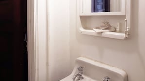 Ein Badezimmer mit einem weißen Waschbecken, einem Spiegel darüber und einem Handtuchhalter.