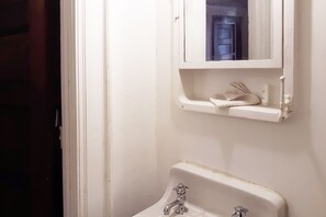 A bathroom with a white sink, a mirror above it, and a towel rack. - Hotel Bradford Main St PA (Bradford)