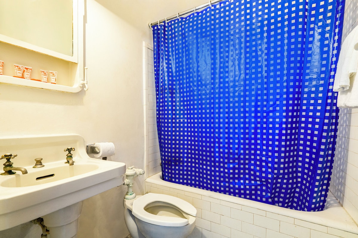 Une salle de bain avec un lavabo blanc, des toilettes et un rideau de douche bleu.