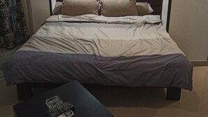 A hotel room with a bed, a bedside table with a remote control, and a wall-mounted light fixture. - Montana Connection, Hurghada (Hurghada)