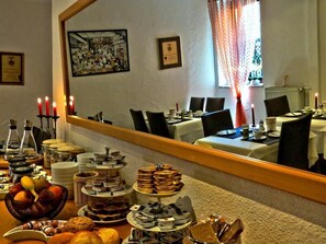 Un comedor con montaje tipo bufé, que incluye diversas opciones de comida y un espejo que refleja la habitación.