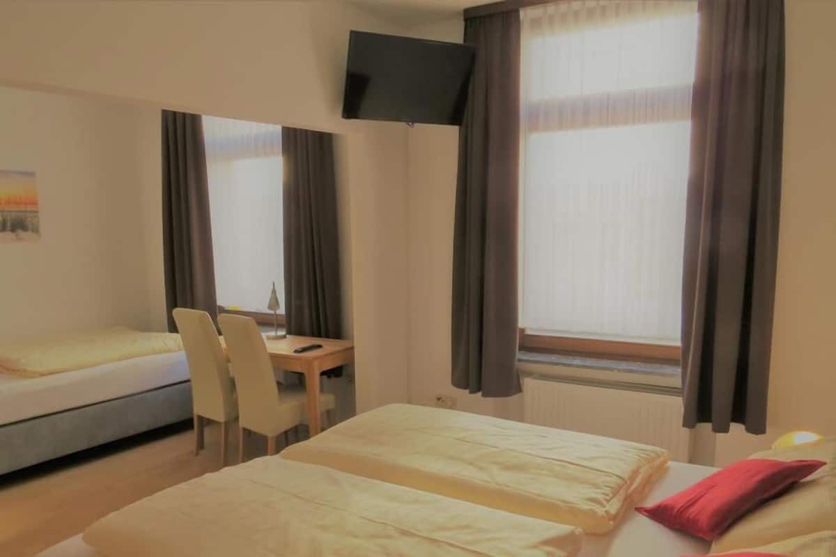 Una camera d'albergo con due letti, una scrivania, una sedia e un televisore.