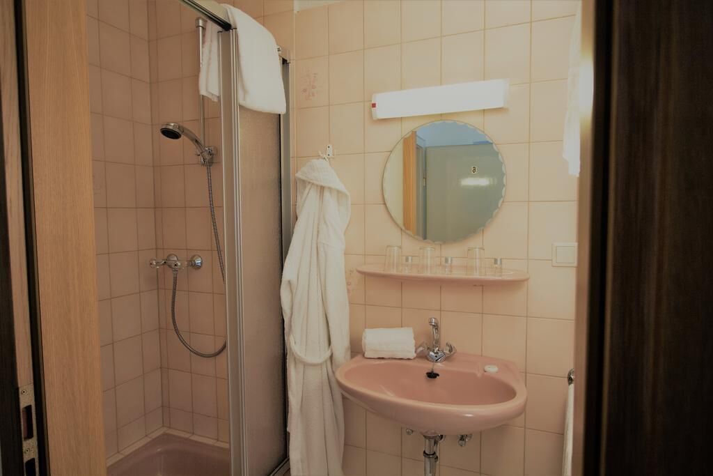 Un baño con ducha, lavamanos y espejo.