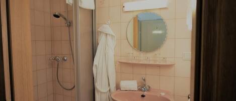 Un baño con ducha, lavamanos y espejo.