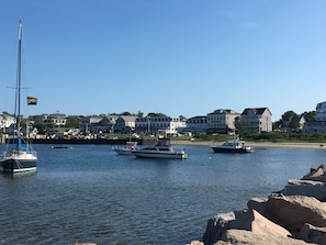 A marina with several boats docked, a clear sky, and buildings in the background.