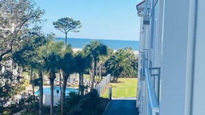 Et hotel med korridor, pool, palmer og havudsigt.