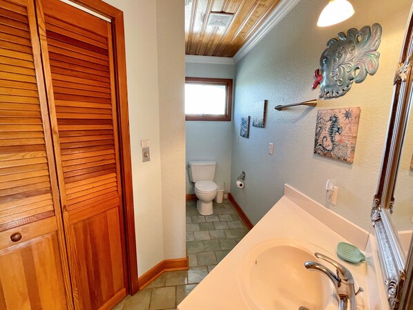 Une salle de bain avec une porte en bois, des toilettes, un lavabo avec un miroir et des éléments décoratifs sur les murs.