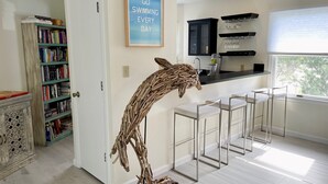 Uma cozinha moderna com área de bar, uma escultura de madeira decorativa e uma estante cheia de livros.