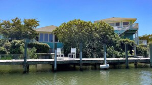 Um imóvel à beira-mar com um cais, uma árvore e uma casa com varanda.