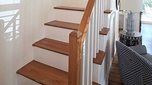 A staircase with wooden steps and white railings, leading to a landing with a view of a pool. - Bragg-Tolson House (Formerly Serendipity): Historic Home with Modern Convenience (Ocracoke)